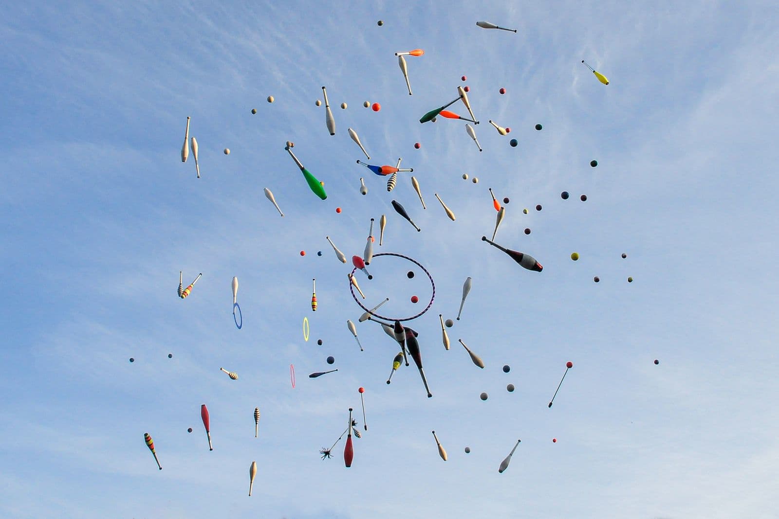 Des massues et des anneaux de jonglerie lancés haut dans un ciel bleu