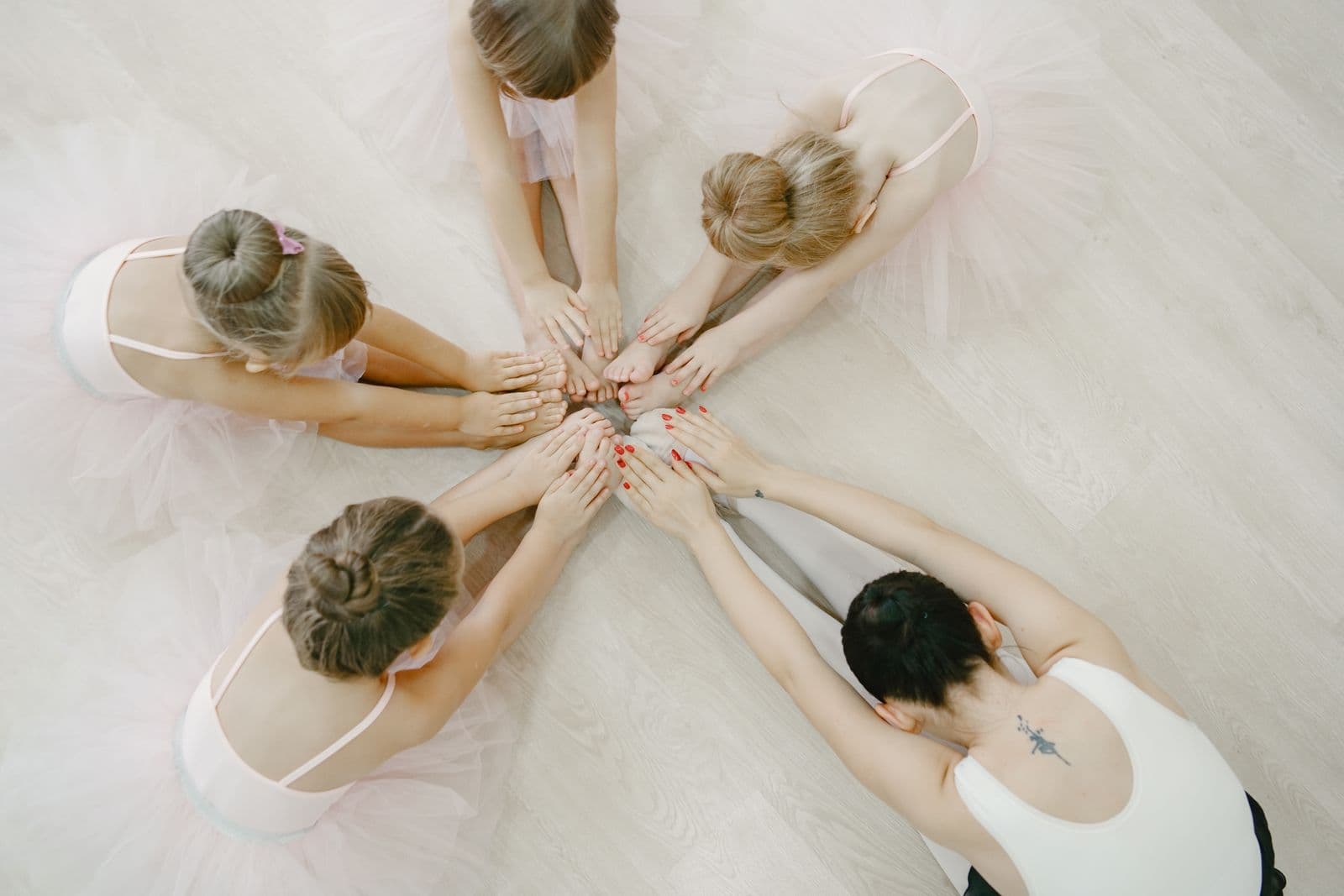 De jeunes élèves de ballet vues d'en haut, en cercle sur le sol du studio, les mains réunies au centre