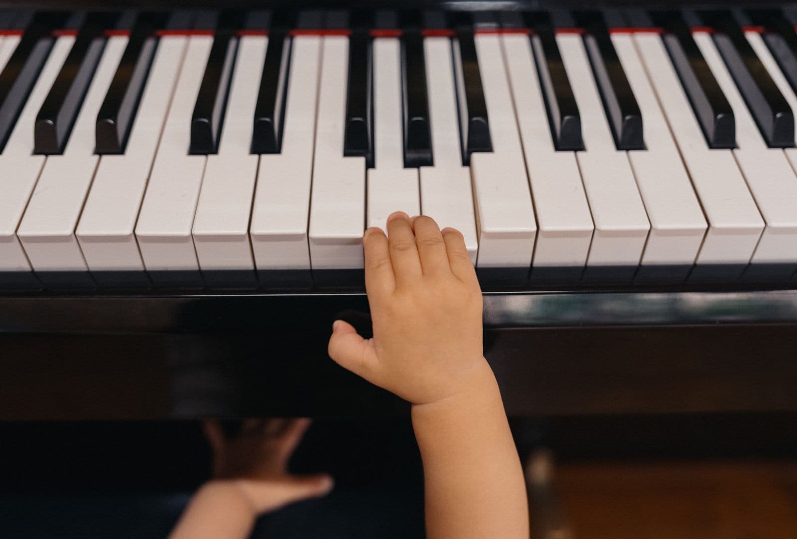 La main d'un jeune enfant qui s'approche des touches d'un piano