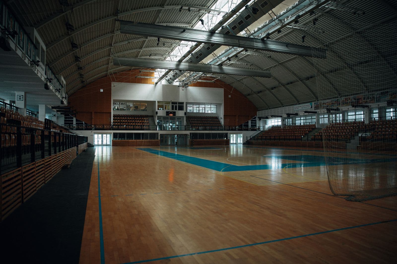 Un aréna sportif intérieur vide avec un terrain en bois et des gradins