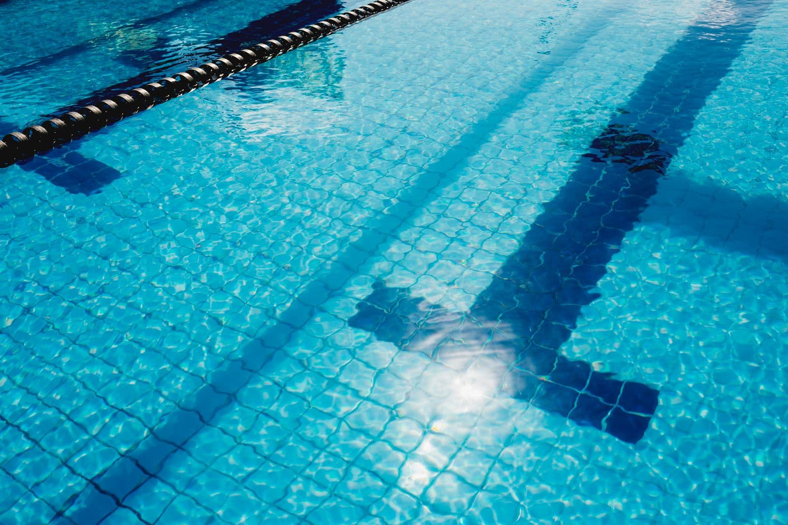 Une piscine ensoleillée à l'eau claire, avec des lignes de couloir
